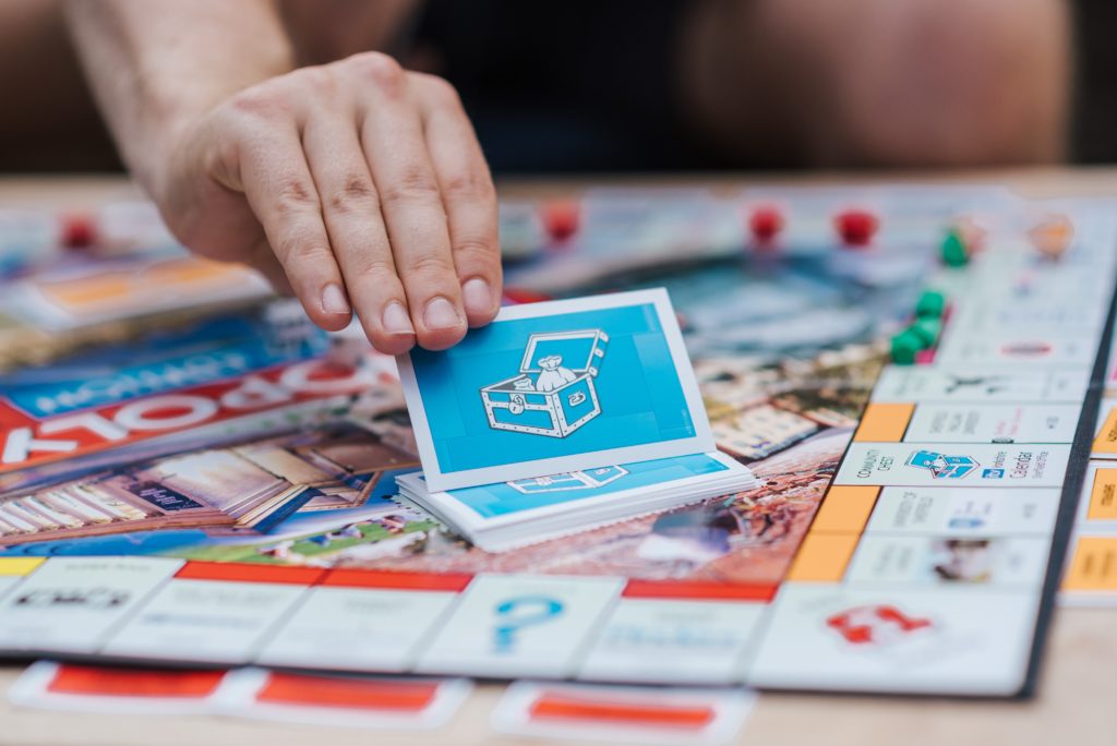 A Monopoly board game player with a Community Chest card in hand.