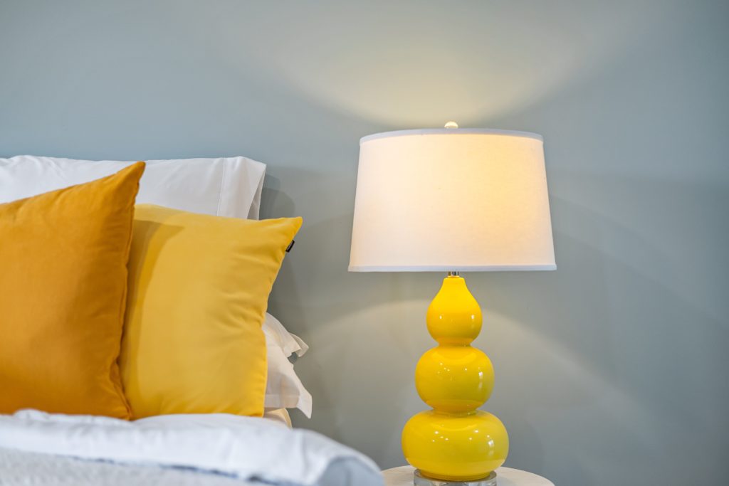 Bedside nightstand and lamp with the light on.