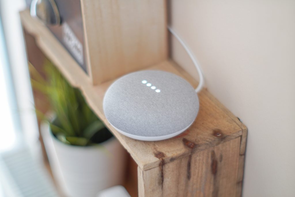 An activated Google Mini on a wooden shelf.